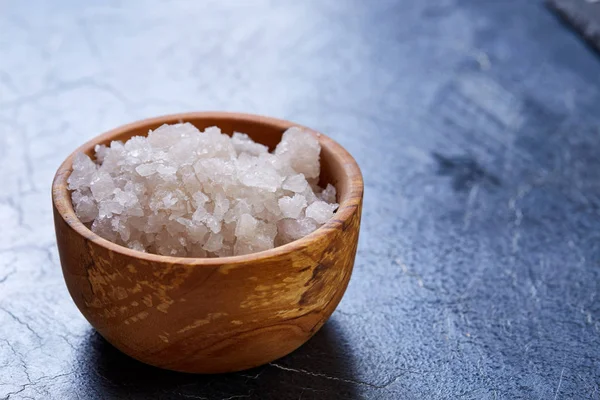 Großes weißes Meersalz in einer natürlichen Holzschale auf dunklem Hintergrund, Draufsicht, Nahaufnahme, selektiver Fokus — Stockfoto