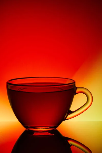 赤と黄色の背景、クローズ アップ、垂直のガラス透明な空茶碗. — ストック写真