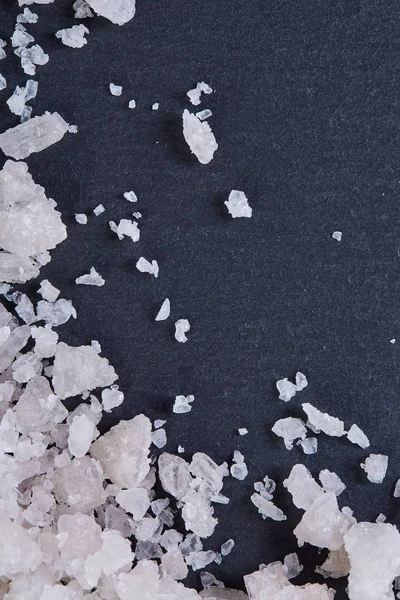 Pile of salt crystals isolated over the dark background, close-up, top view, macro, selective focus, vertical