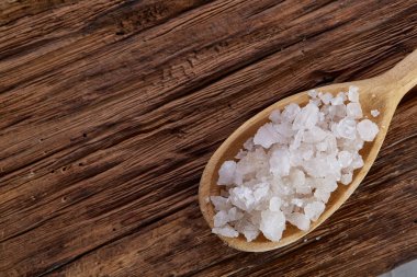 Kristal deniz tuzu bir tahta kaşık koyu vintage ahşap arka plan, üstten görünüm, yakın çekim, seçici odak içinde.