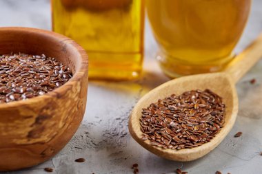 Işık cam şişede kase ve keten tohumu yağı keten tohumu dokulu arka plan, üstten görünüm, yakın çekim, seçici odak