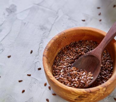 Işık cam şişede kase ve keten tohumu yağı keten tohumu dokulu arka plan, üstten görünüm, yakın çekim, seçici odak