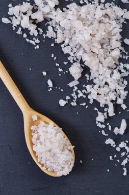 Kristal deniz tuzu bir tahta kaşık koyu arka plan, üstten görünüm, yakın çekim, seçici odak içinde.