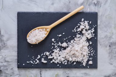 Kristal deniz tuzu bir tahta kaşık koyu arka plan, üstten görünüm, yakın çekim, seçici odak içinde.