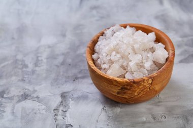 Büyük beyaz deniz tuzu bir doğal ahşap kase beyaz arka plan, üstten görünüm, yakın çekim, seçici odak