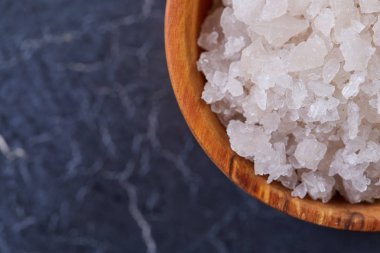 Büyük beyaz deniz tuzu bir doğal ahşap kase beyaz arka plan, üstten görünüm, yakın çekim, seçici odak