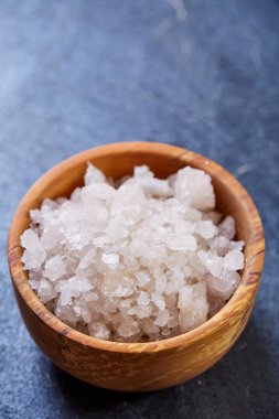 Büyük beyaz deniz tuzu bir doğal ahşap kase beyaz arka plan, üstten görünüm, yakın çekim, seçici odak