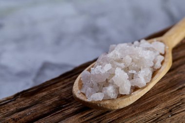 Kristal deniz tuzu bir tahta kaşık koyu vintage ahşap arka plan, üstten görünüm, yakın çekim, seçici odak içinde.