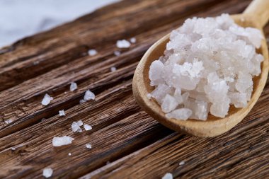 Kristal deniz tuzu bir tahta kaşık koyu vintage ahşap arka plan, üstten görünüm, yakın çekim, seçici odak içinde.