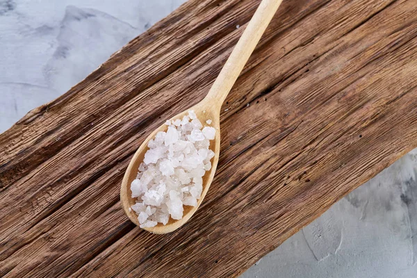 Sal marina cristalina en una cuchara de madera sobre fondo de madera oscura vintage, vista superior, primer plano, enfoque selectivo . — Foto de Stock