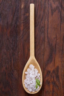 Kristal deniz tuzu bir tahta kaşık koyu vintage ahşap arka plan, üstten görünüm, yakın çekim, seçici odak içinde.