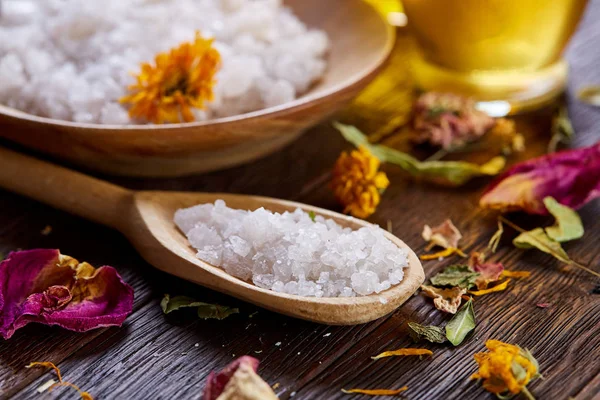 SPA concept: composition of spa treatment with natural sea salt, aromatic oil and flowers on wooden background