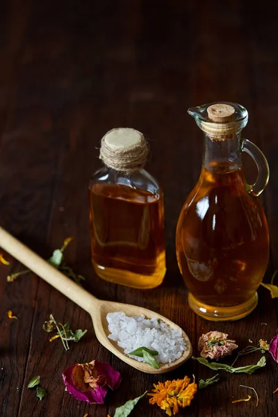 SPA concept: composition of spa treatment with natural sea salt, aromatic oil and flowers on wooden background