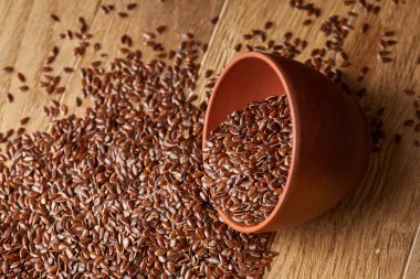 Linseeds bir rustik arka plan, yakın çekim, sığ alan, seçici odak derinliği ile devrilmiş bir ahşap kase