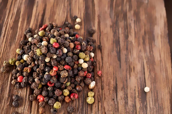 Draufsicht auf schwarze, rote und weiße Pfefferkörner isoliert auf Holzgrund, geringe Schärfentiefe. — Stockfoto