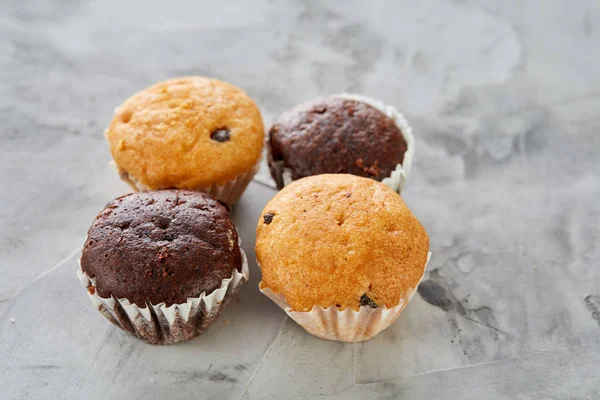 Muffin gustosi disposti a disegno su sfondo strutturato chiaro, primo piano, profondità di campo poco profonda, messa a fuoco selettiva . — Foto Stock