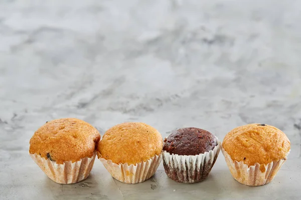 Lekkere muffins gerangschikt in patroon op licht gestructureerde achtergrond, close-up, ondiepe diepte van veld, selectieve aandacht. — Stockfoto