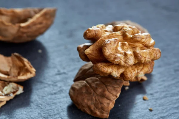 Top view close-up shot of cracked walnuts on dark background, shallow depth of field, macro