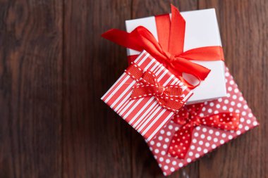 Küçük kırmızı renk kutusunda şerit ve ahşap arka plan, üstten görünüm, yakın çekim yay ile tatil hediye ile natürmort