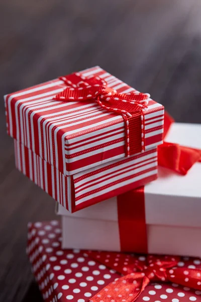 Натюрморт з святковим подарунком у маленькій червоній коробці зі стрічкою та бантом на дерев'яному тлі, вид зверху, крупним планом — стокове фото