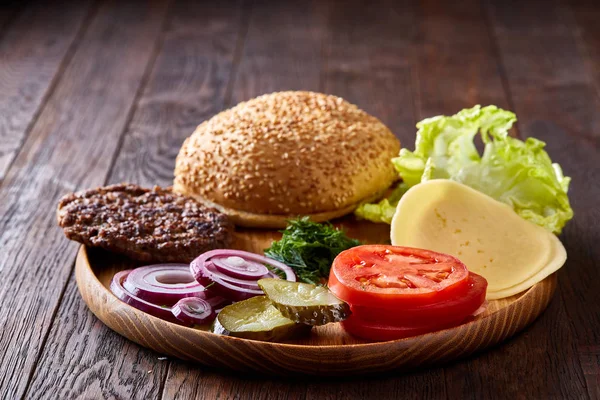 Lahodný hamburger ingredience umělecky uspořádány na dřevěné desce, detail, horní pohled, Selektivní ostření — Stock fotografie