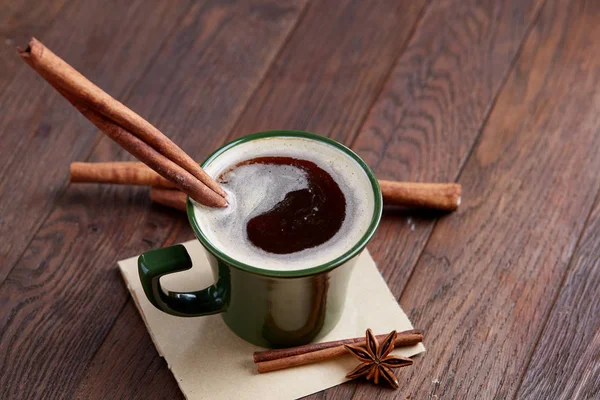 Taza de café cremoso con canela y anís estrellado en una mesa de madera, vista superior, primer plano, enfoque selectivo —  Fotos de Stock