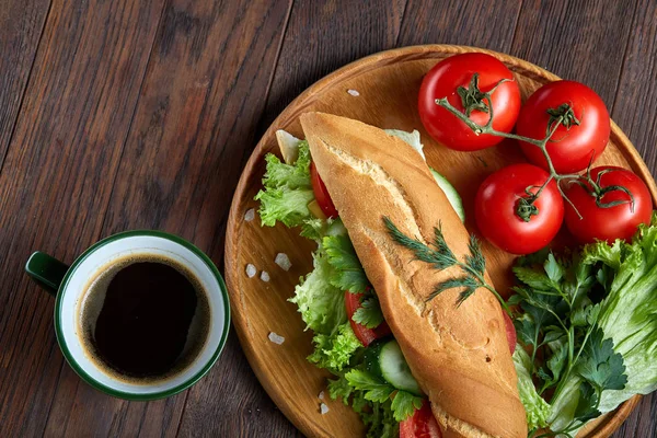 Panino fresco con lattuga, pomodori, formaggio su piatto di legno, tazza di caffè su fondo di legno, messa a fuoco selettiva — Foto Stock