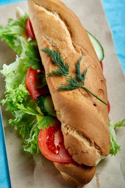 Fresh and tasty sandwich with cheese and vegetables on paper plate over blue background, selective focus, top view — Stock Photo, Image