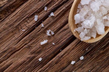 Kristal deniz tuzu bir tahta kaşık koyu arka plan, üstten görünüm, yakın çekim, seçici odak içinde.