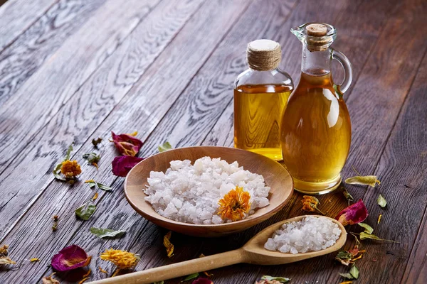 SPA concept: composition of spa treatment with natural sea salt, aromatic oil and flowers on wooden background