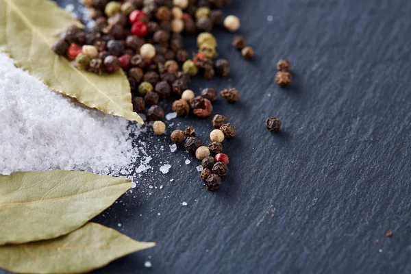 Composition of bay laurel leaf with peppercorn and salt isolated on dark background, top view, close-up, selective focus