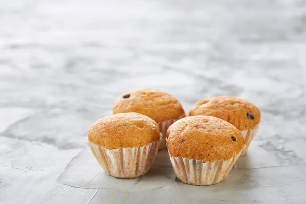 Lekkere muffins gerangschikt in patroon op licht gestructureerde achtergrond, close-up, ondiepe diepte van veld, selectieve aandacht. — Stockfoto