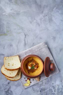 Toprak kap beyaz peçete üzerinde kabak çorbası dokulu arka plan, yakın çekim, seçici odak, üstten görünüm.