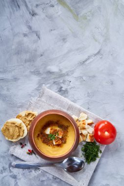 Toprak kap beyaz peçete üzerinde kabak çorbası dokulu arka plan, yakın çekim, seçici odak, üstten görünüm.