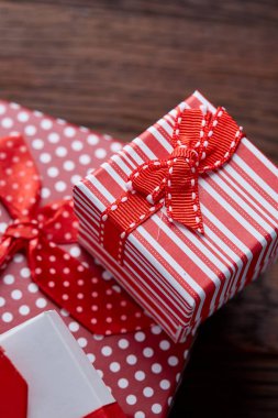 Küçük kırmızı renk kutusunda şerit ve ahşap arka plan, üstten görünüm, yakın çekim yay ile tatil hediye ile natürmort