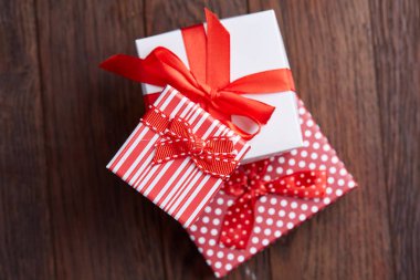 Küçük kırmızı renk kutusunda şerit ve ahşap arka plan, üstten görünüm, yakın çekim yay ile tatil hediye ile natürmort