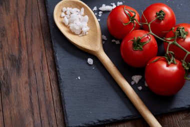 Taze üzüm domates, biber ve tuz ahşap zemin, seçici odak üzerine tahta kaşık ile vejetaryen natürmort