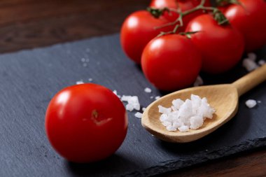 Taze üzüm domates, biber ve tuz ahşap zemin, seçici odak üzerine tahta kaşık ile vejetaryen natürmort