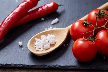 Taze üzüm domates, biber ve tuz ahşap zemin, seçici odak üzerine tahta kaşık ile vejetaryen natürmort