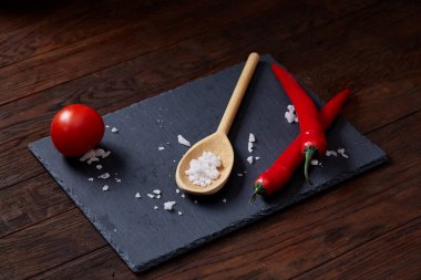 Taze üzüm domates, biber ve tuz ahşap zemin, seçici odak üzerine tahta kaşık ile vejetaryen natürmort