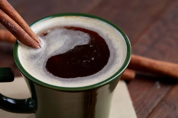 Taza de café cremoso con canela y anís estrellado en una mesa de madera, vista superior, primer plano, enfoque selectivo —  Fotos de Stock