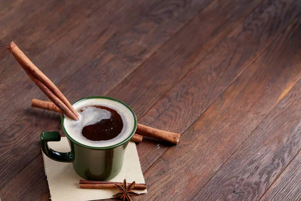 Taza de café cremoso con canela y anís estrellado en una mesa de madera, vista superior, primer plano, enfoque selectivo —  Fotos de Stock