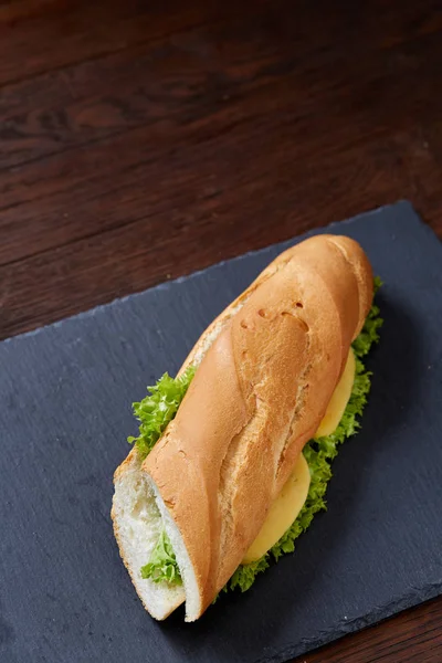 チーズと野菜の木製の背景、選択と集中でまな板の上の新鮮でおいしいサンドイッチ. — ストック写真