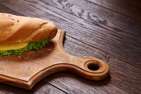 Sandwich fresco y sabroso con queso y verduras en tabla de cortar sobre fondo de madera, enfoque selectivo . —  Fotos de Stock