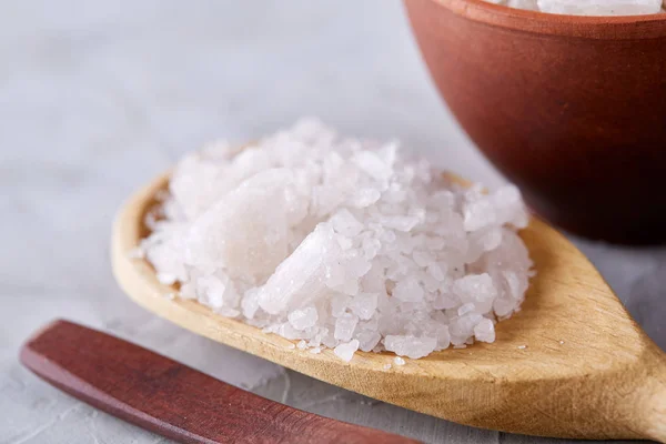 Conceptual composition of salt and pepper on spoons and bowls over light background, top view, close-up