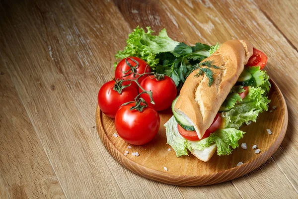 Fresh sandwich with lettuce, tomatoes, cheese on wooden plate, cup of coffee on rustic background, selective focus — Stock Photo, Image
