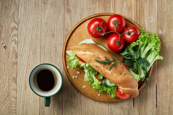 Sandwich fresco con lechuga, tomates, queso en plato de madera, taza de café sobre fondo rústico, enfoque selectivo — Foto de Stock