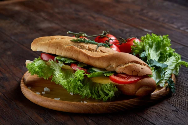 Panino fresco con lattuga, pomodori, formaggio su piatto di legno, tazza di caffè su sfondo rustico, focus selettivo — Foto Stock