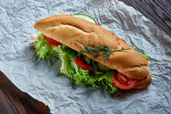 Fresh and tasty sandwich with cheese and vegetables on paper napkin over wooden background, selective focus, top view — Stock Photo, Image