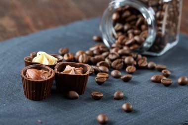 Ahşap zemin, seçici odak üzerine devrilmiş cam sürahi kahve çekirdekleri ve çikolata şekerleme ile yan görünüm